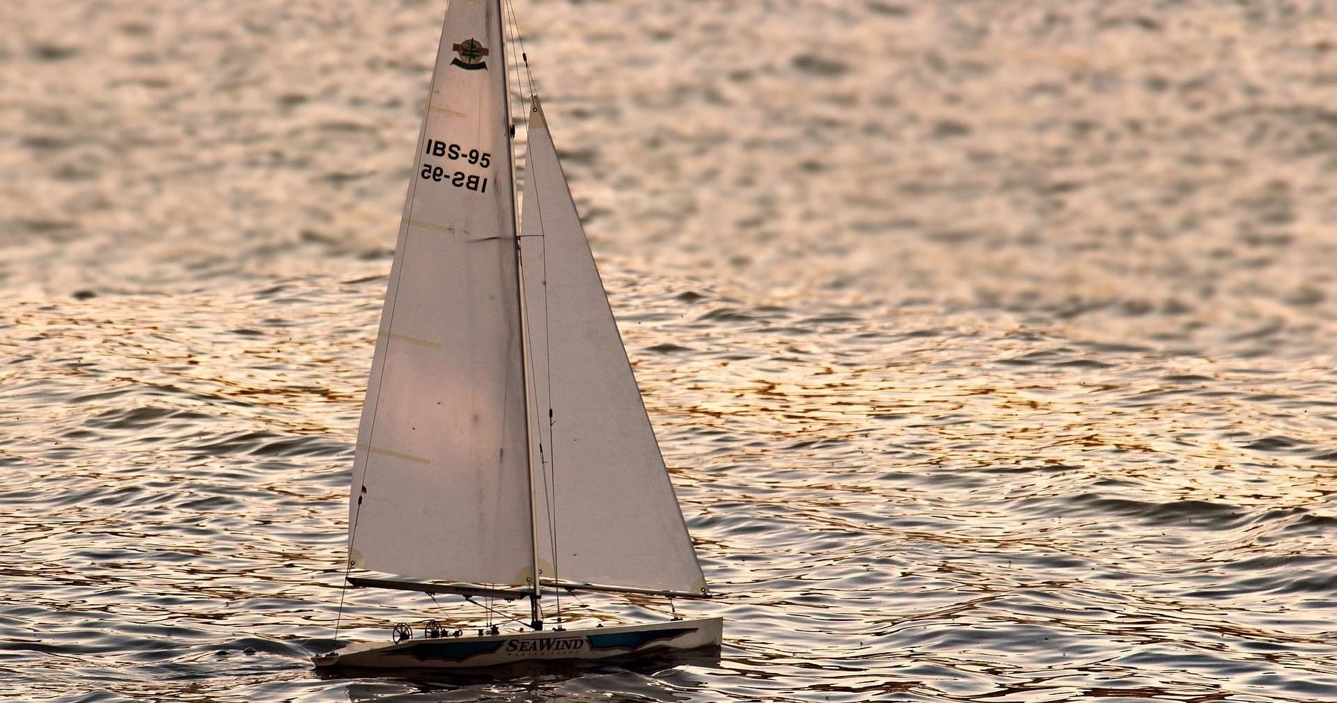 Classic sailboat cruising at sunset on shimmering coastal waters