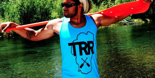 Guide with paddle along Truckee River in green riverside scene