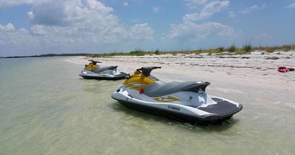 Parked jet skis on shallow sandbar at sunny beach shore