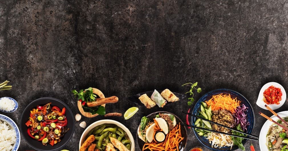 Assorted Asian bowls and noodles styled on tabletop for dining