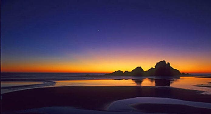 Sunset beach with sea stacks and reflective tide pools, coastal twilight