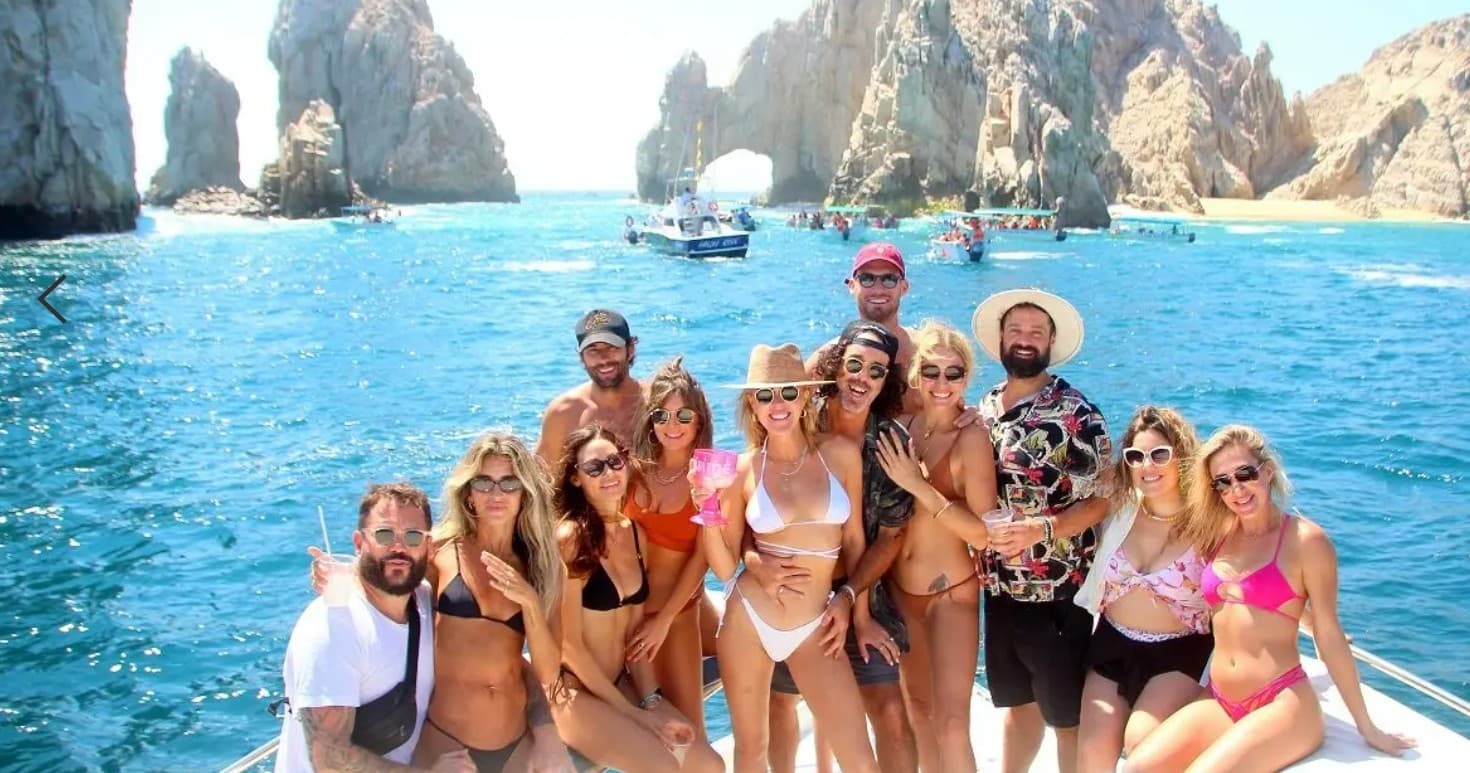 Group boat tour by Cabo rock arches with swimmers and scenery