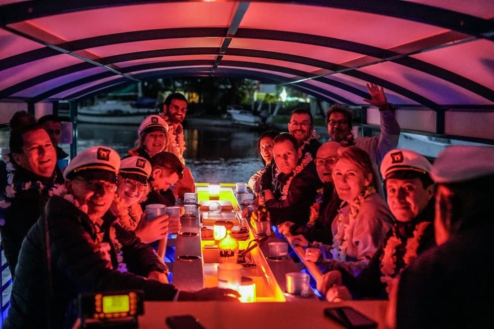 Nighttime group on illuminated paddle pub boat party on water