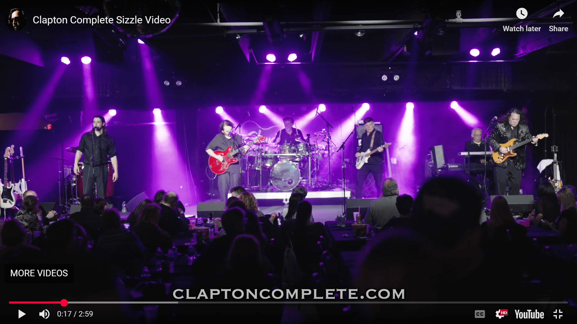 Live band performing on indoor concert stage with purple lights