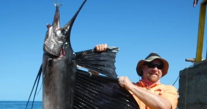 Angler hauling sailfish offshore during sportfishing in Pacific