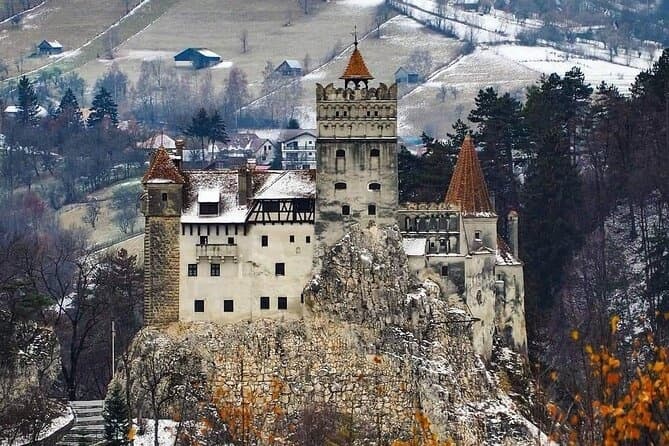 Medieval castle perched on rocky hill in snowy forest landscape