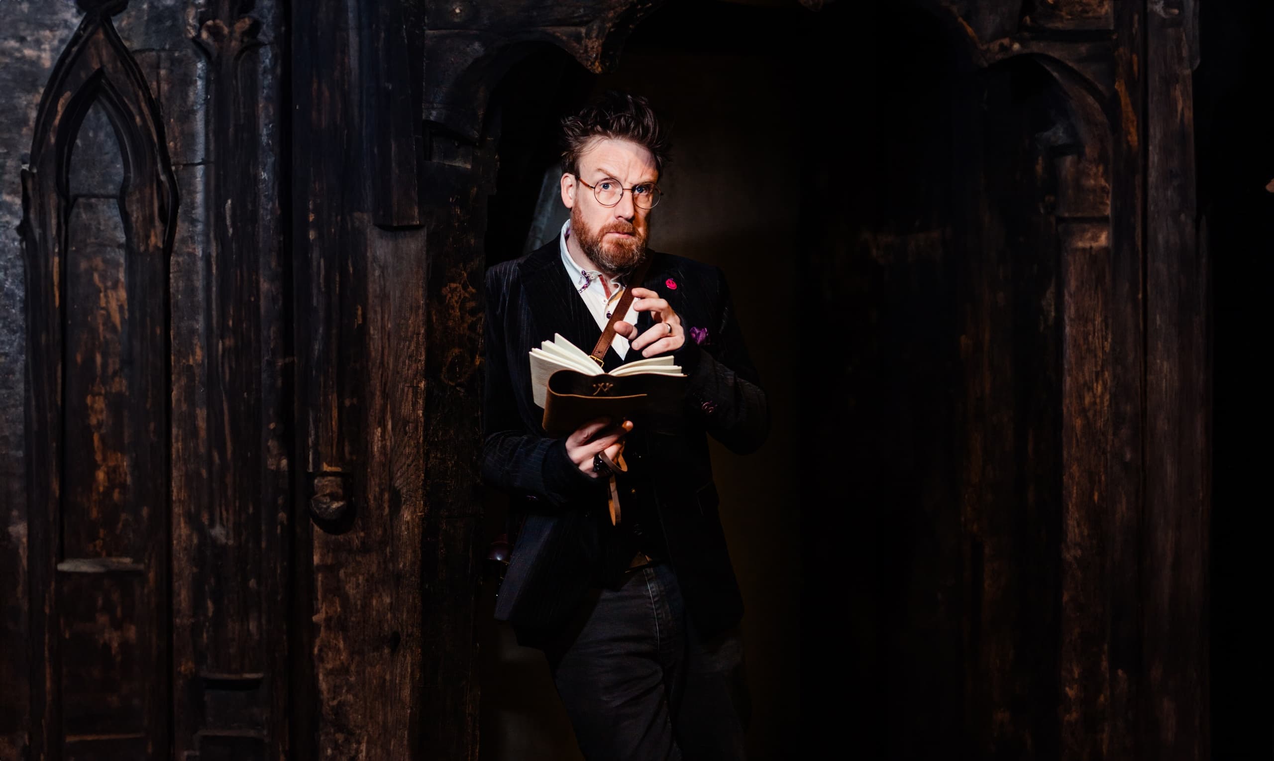 Guide reading from book in Gothic doorway during historic tour