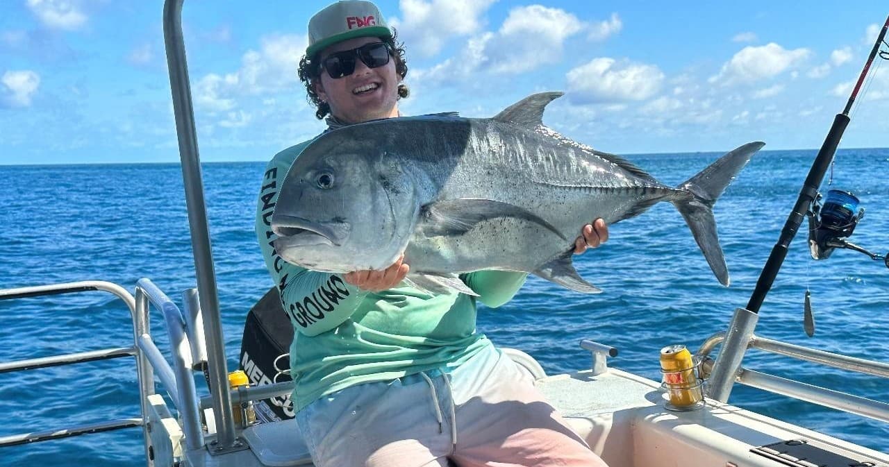 Angler holding large offshore fish on charter boat in open ocean