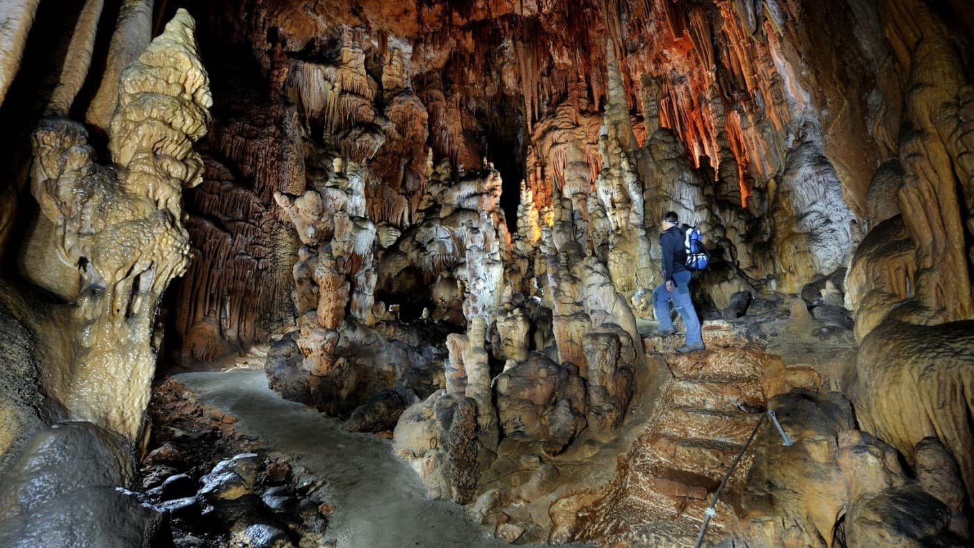 Exploring limestone cave with dramatic stalactites and formations