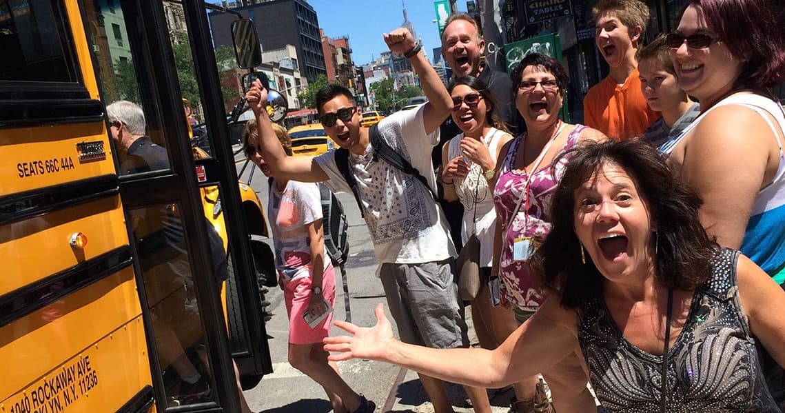 Happy food tour group boarding a city tour bus on street