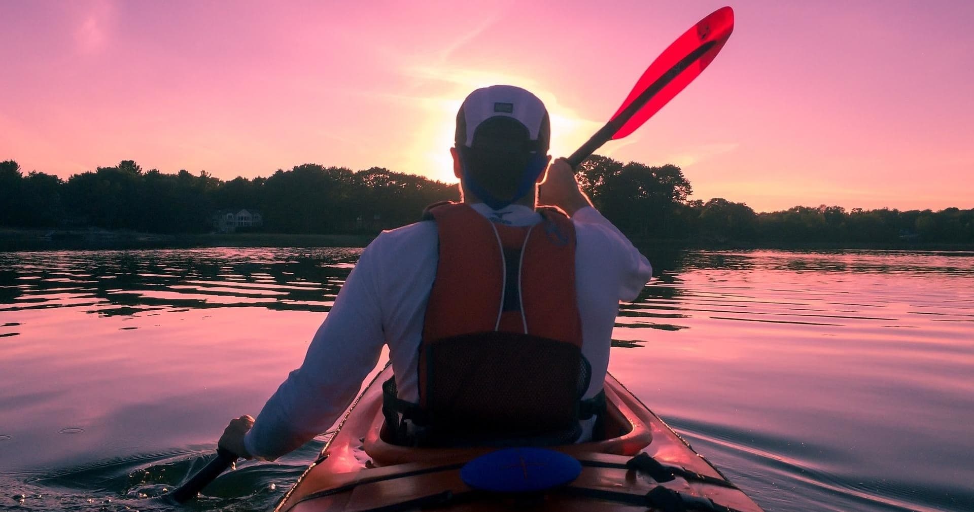 Solo kayaker paddling at sunset on calm Cape Cod waters