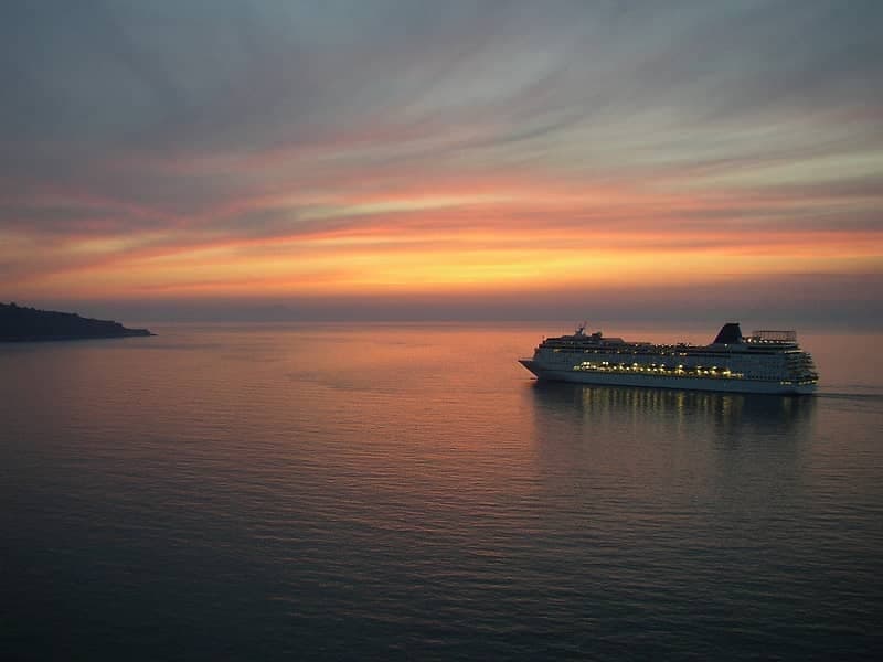 Cruise ship at sunset on calm open sea, evening voyage view