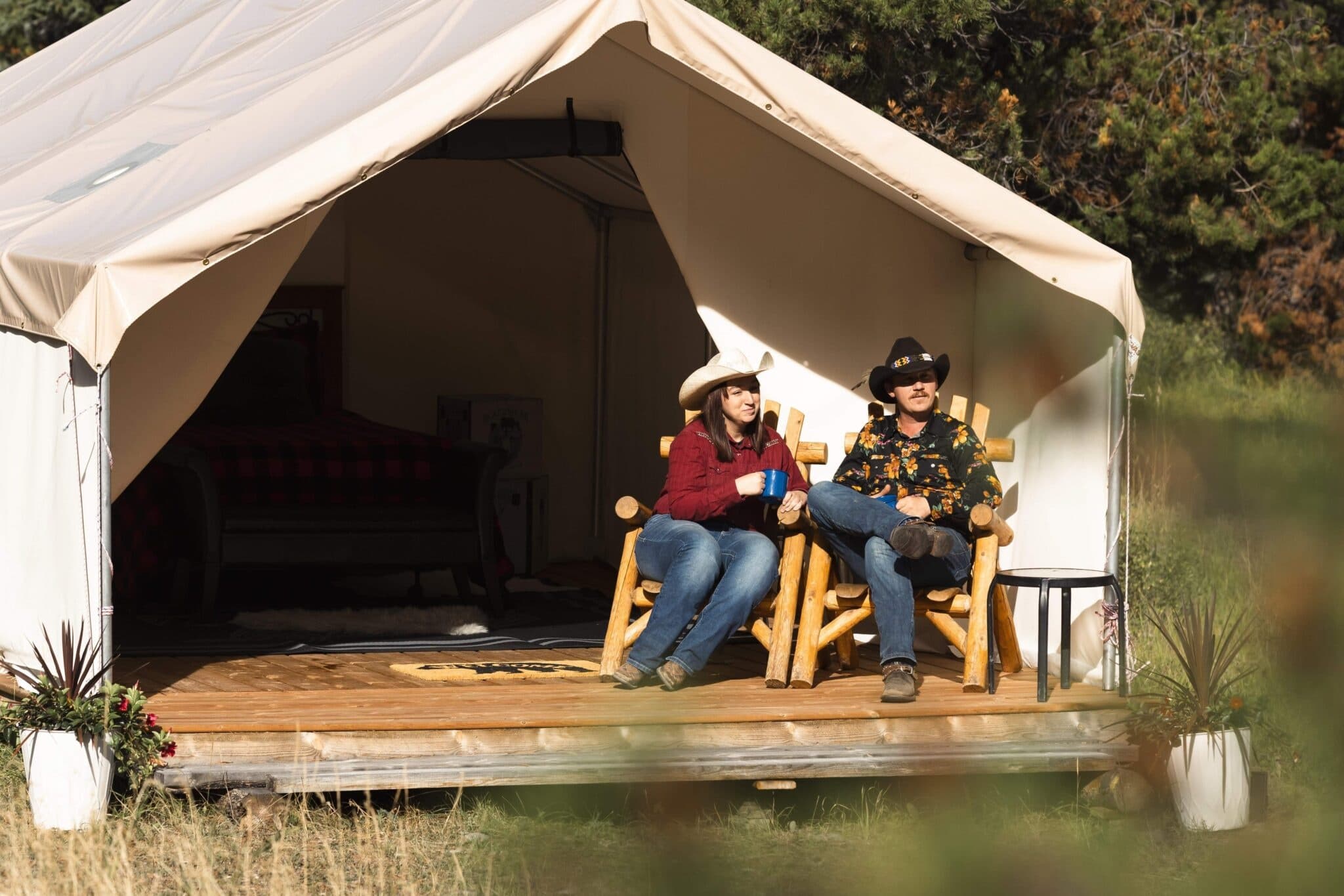 Couple glamping on tent porch enjoying rural lodge outdoors