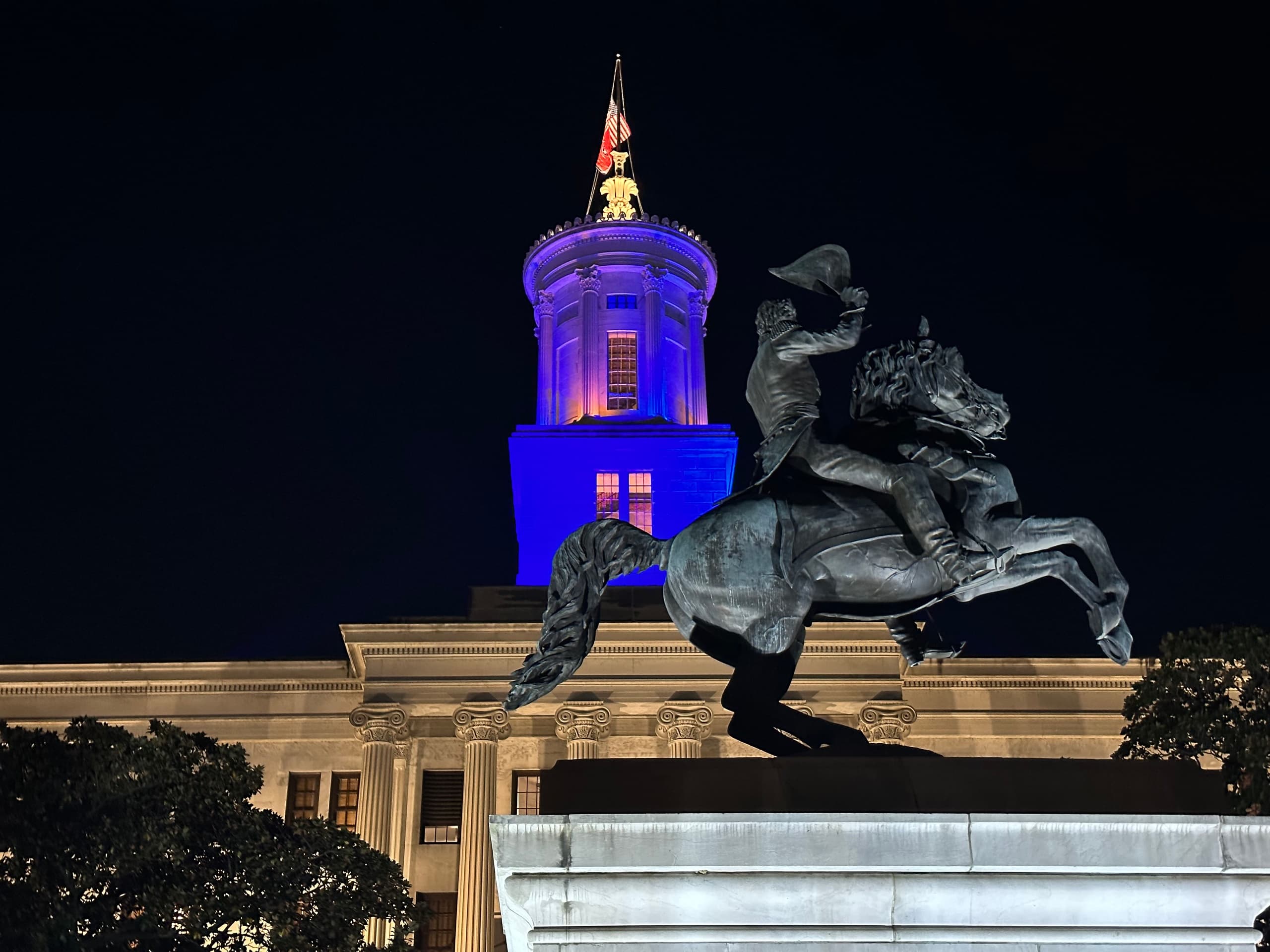 Nighttime equestrian statue and lit civic building in Nashville square