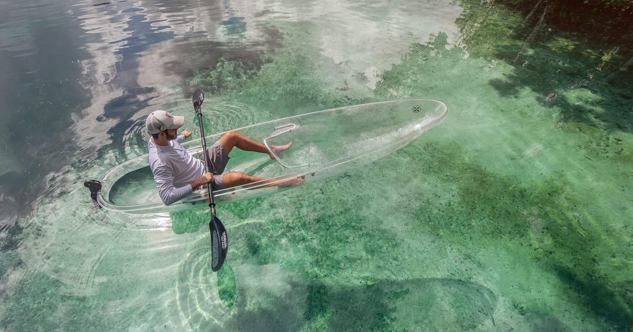 Solo kayaker in clear tropical spring, paddling over seagrass