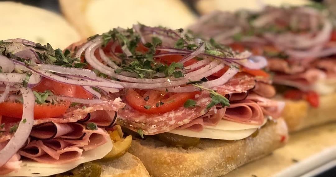 Layered Italian deli sandwich with salami, cheese, onions closeup