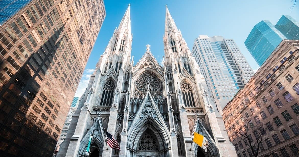 Gothic cathedral facade between skyscrapers, urban sightseeing tour