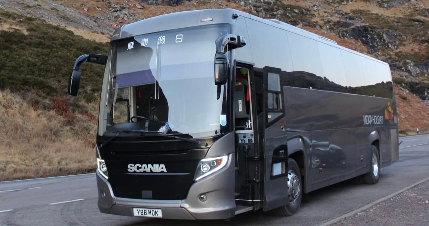 Tour coach parked on mountain road showcasing scenic Highlands drive