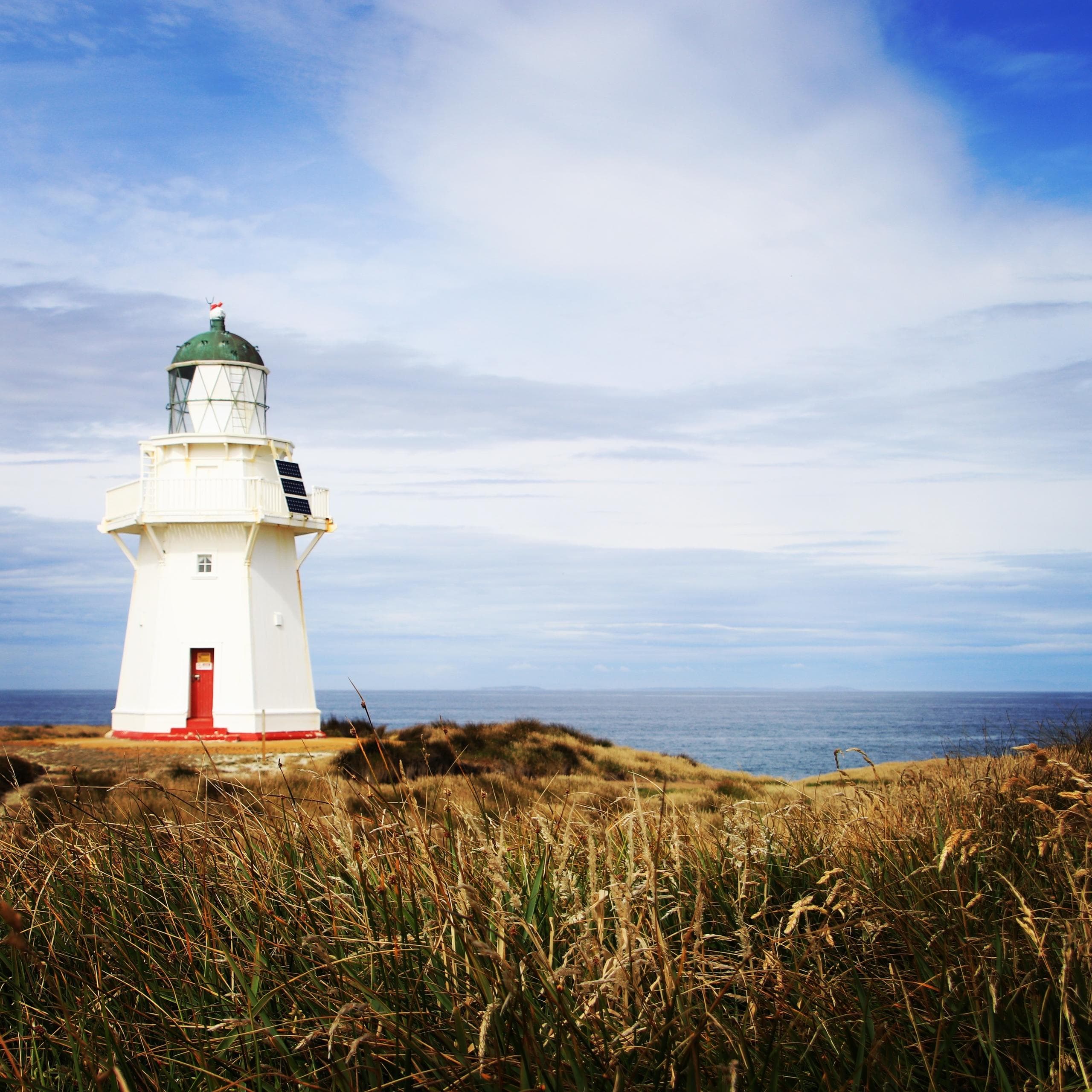 White lighthouse on coastal headland with ocean vista