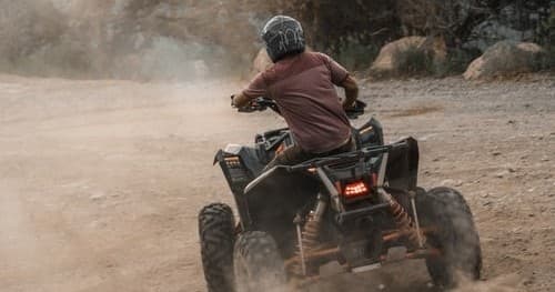 ATV rider kicking up dust on desert dirt trail off-road