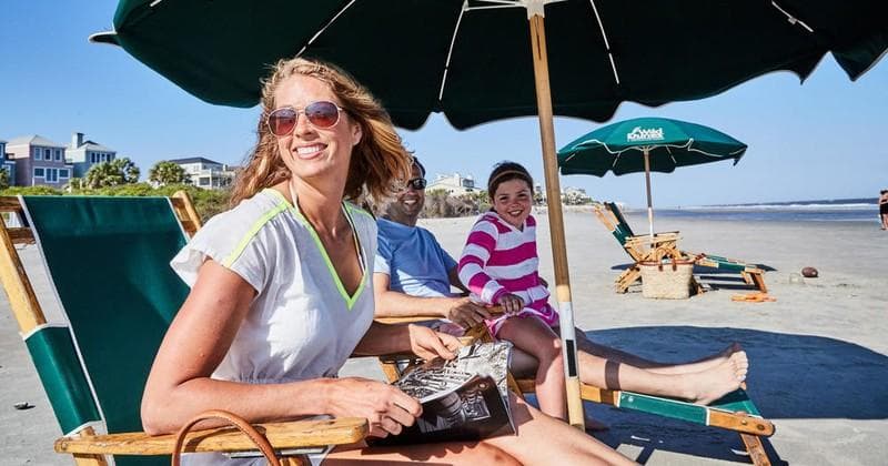 Couple lounging on beach chairs under umbrellas at oceanfront