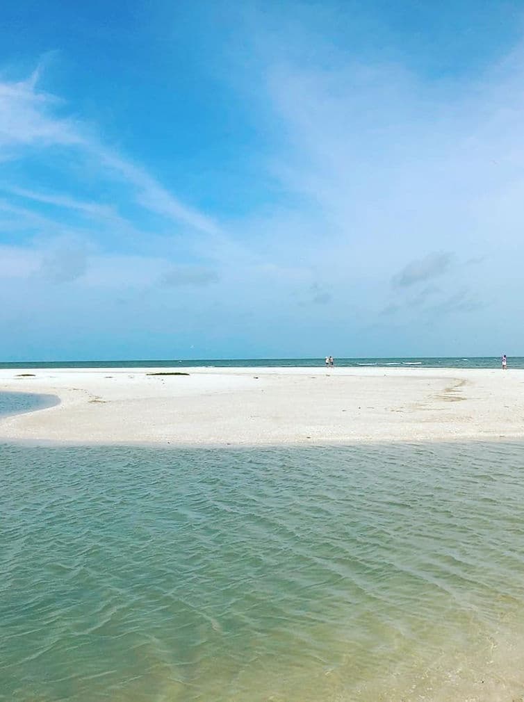 Sandbar and turquoise shallow waters on tropical island beach