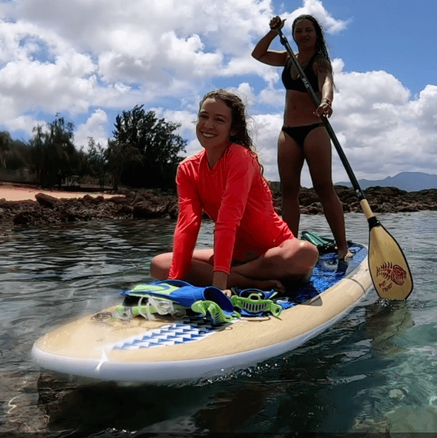 Stand-up paddleboarders enjoying calm bay near tropical beach