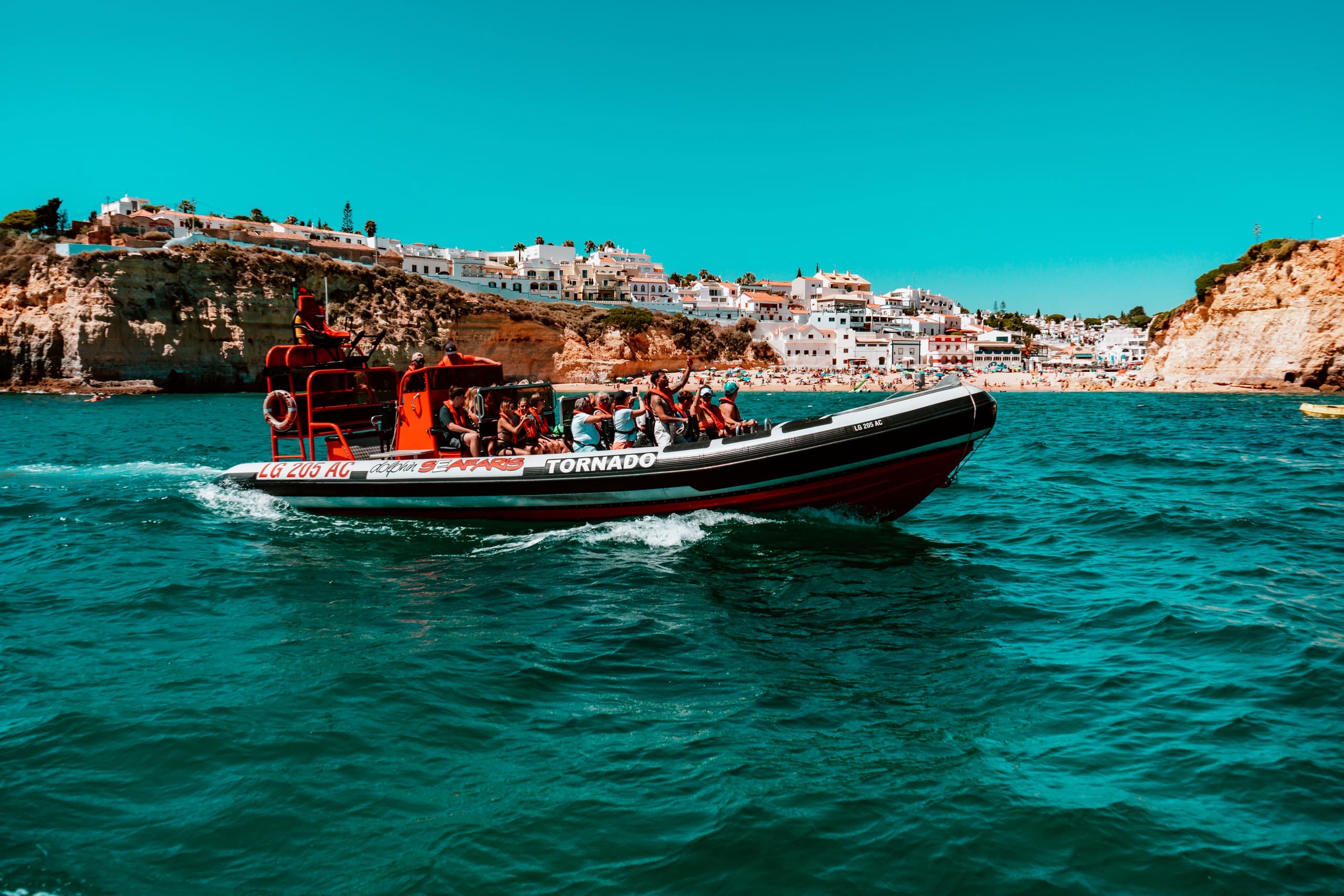 Rigid inflatable boat cruising turquoise water near coastal town