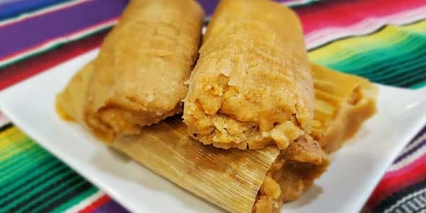 Steamed tamales on corn husks, colorful Mexican table setting