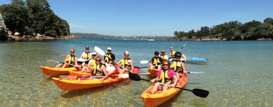 Group of kayakers launching and paddling in coastal inlet