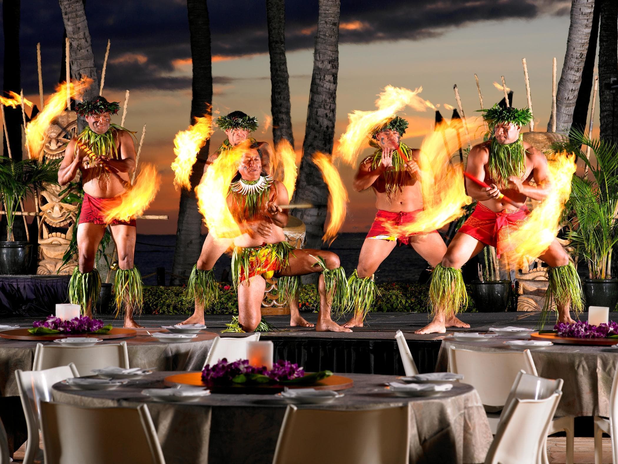 Group of Hawaiian fire dancers performing at beachfront luau in Maui