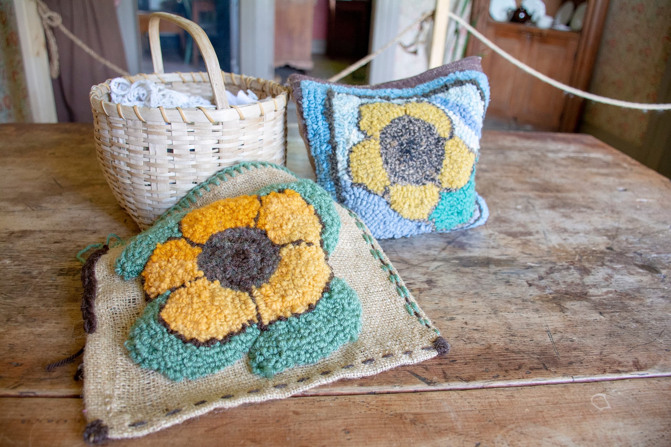Handmade floral hooked pillows on rustic wooden table indoors