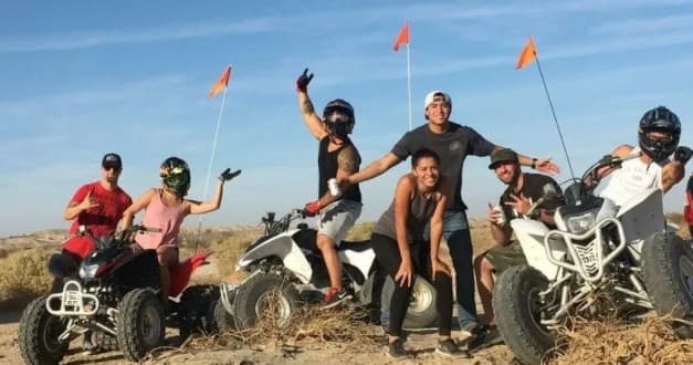 Group on ATVs posing on sandy desert trail during outdoor tour