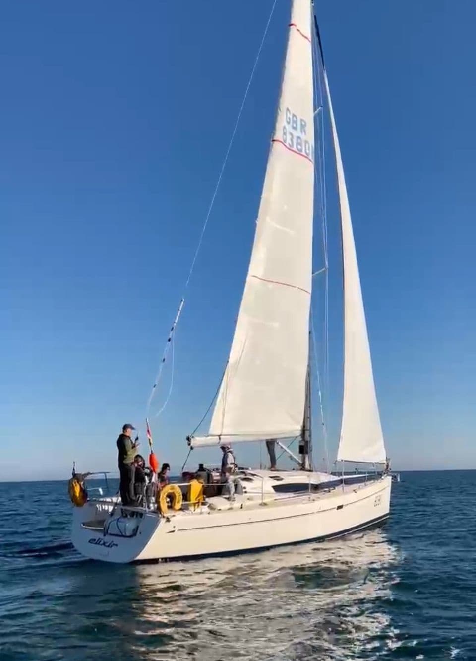 Sailing trip on calm sea near coast with crew aboard small yacht