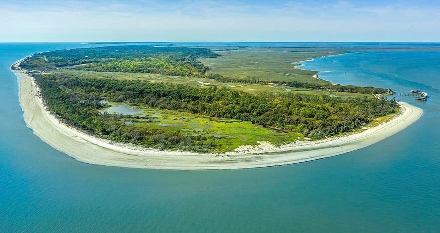 Curved island shoreline aerial showcasing sandy beach and greenery