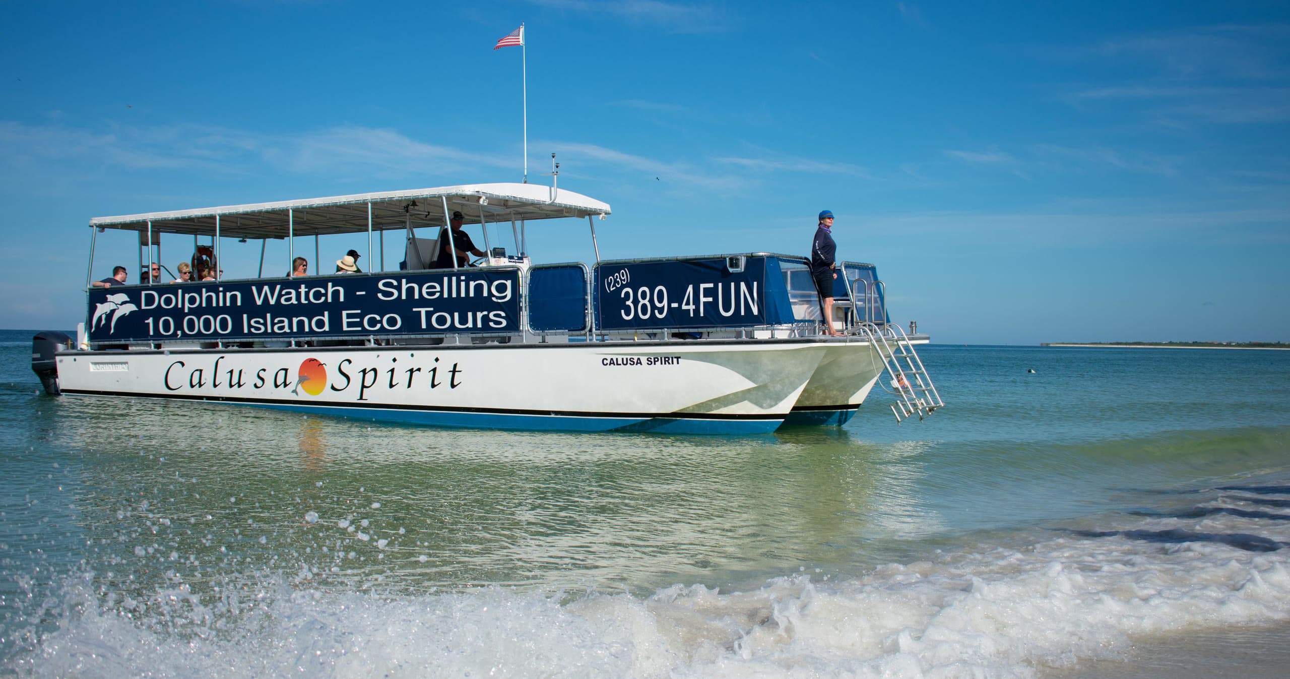 Tour boat on calm Gulf waters near sandy beach, Marco Island FL