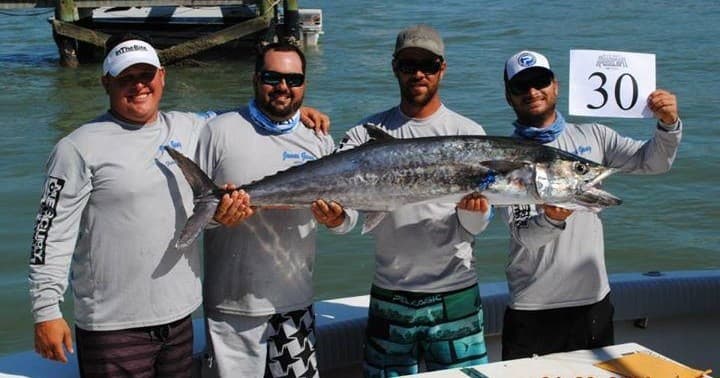 Crew displaying kingfish catch on deck at coastal deep-sea fishing trip