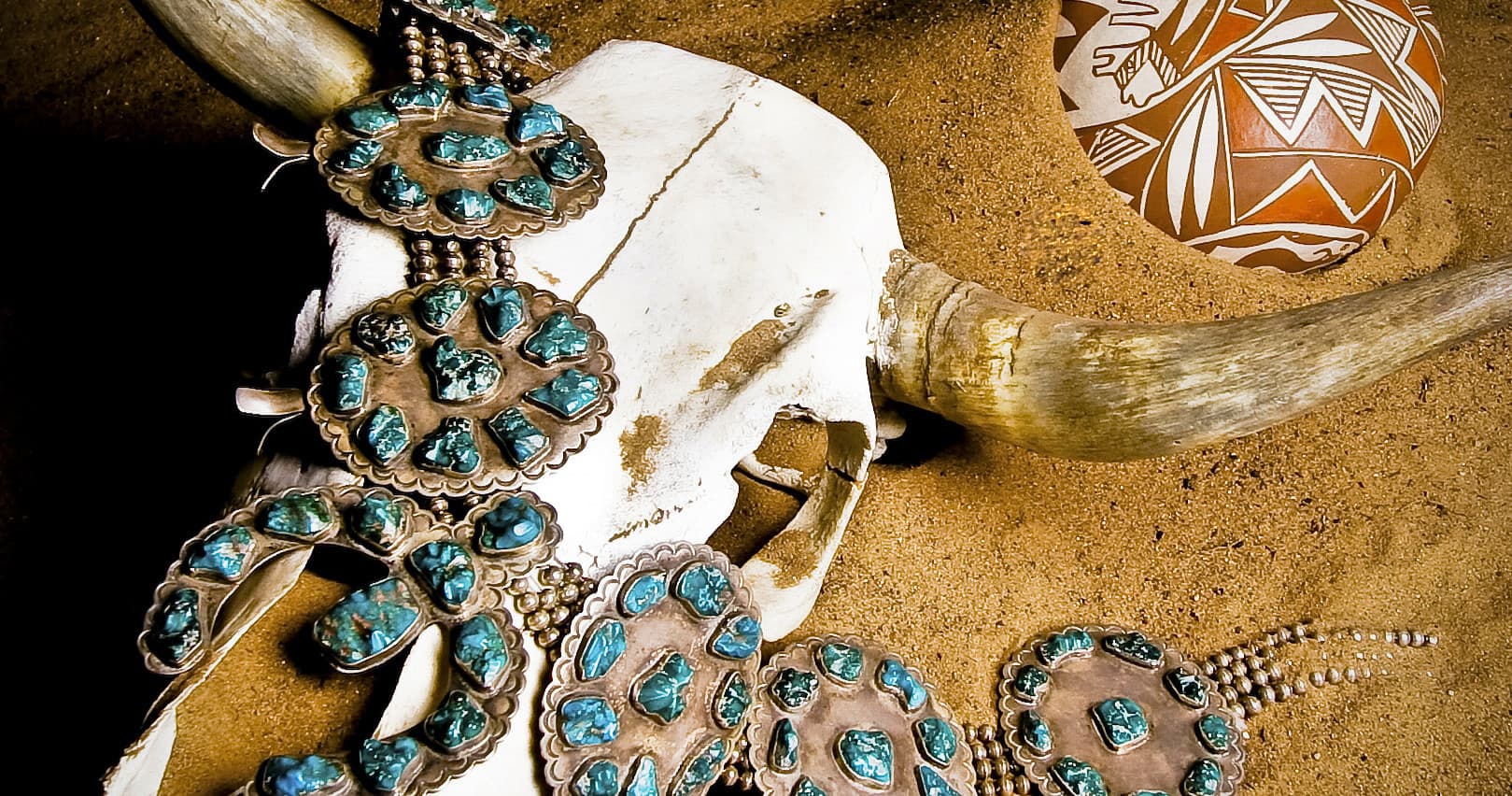 Decorated bison skull adorned with turquoise jewelry, exhibit piece