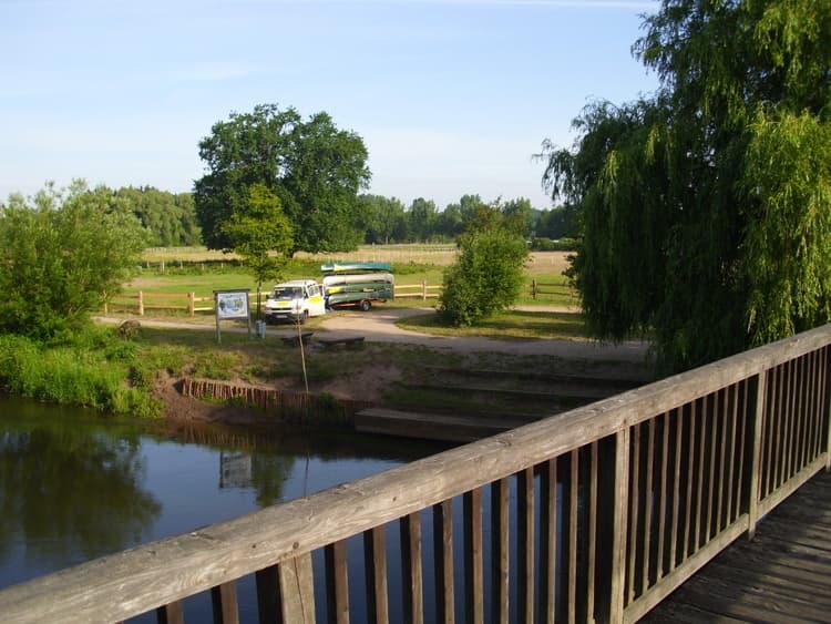 Riverside wooden railing view overlooking meadow and river