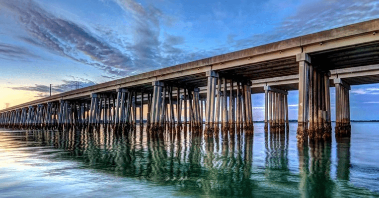 Long pier bridge over calm coastal waters at sunset