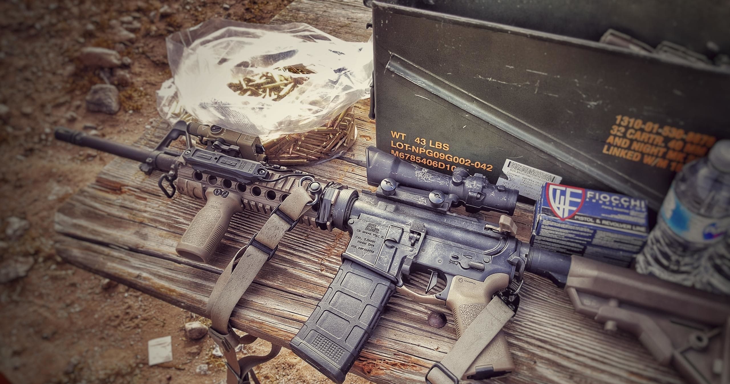 Assault rifles staged on wooden bench at outdoor shooting range