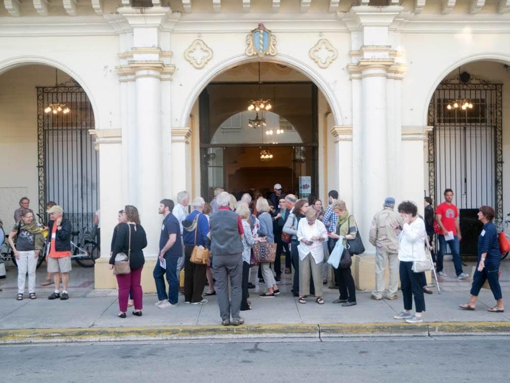 Tour group gathering outside historic theater entrance on street