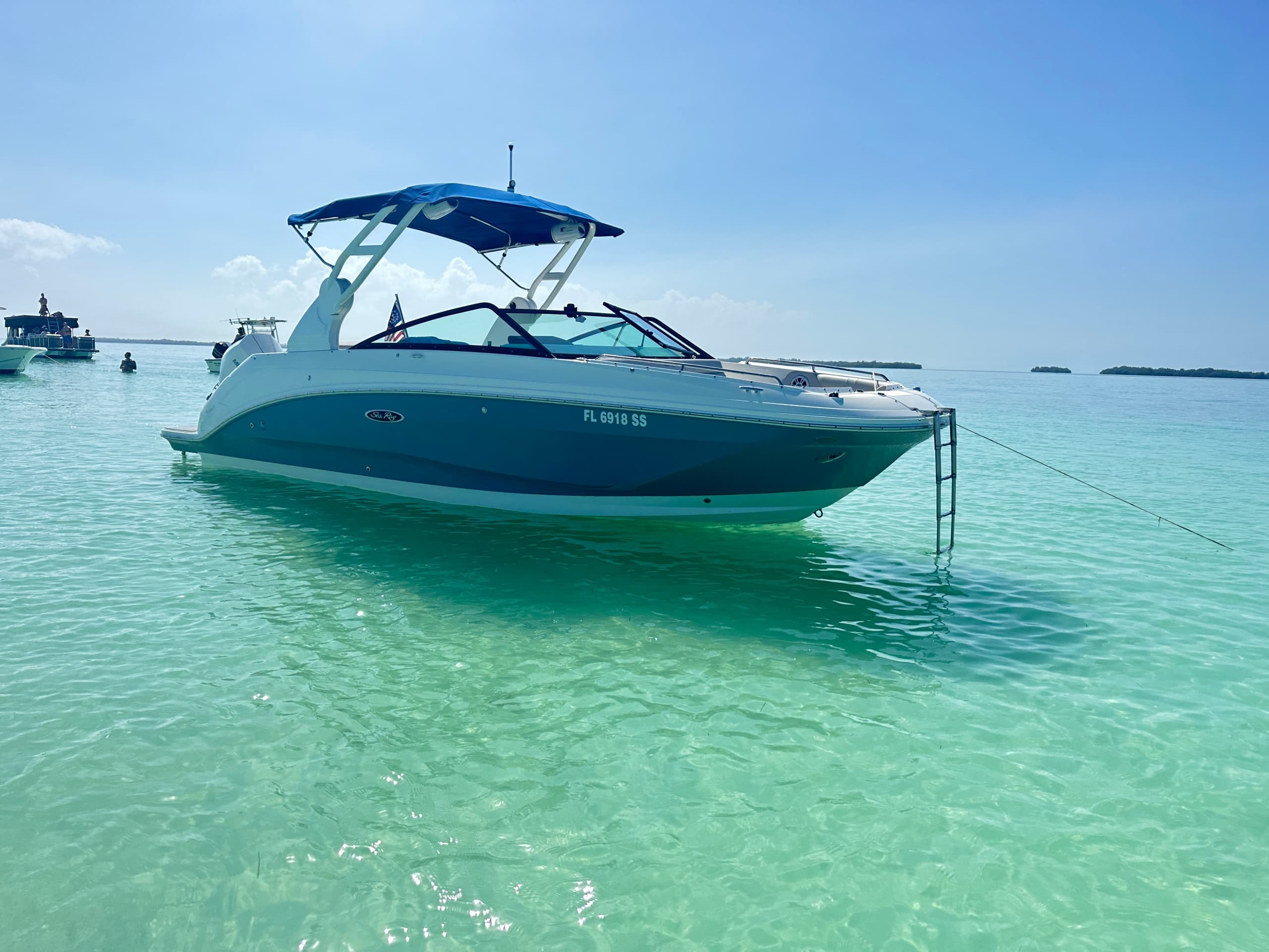 Bow-side view of boat floating above clear sandbar waters