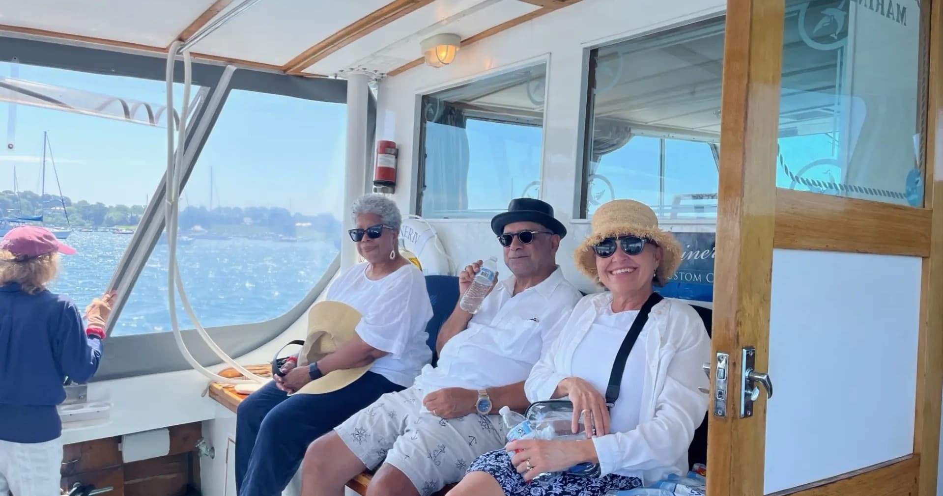 Group enjoying sheltered harbor cruise inside wooden cabin, Newport