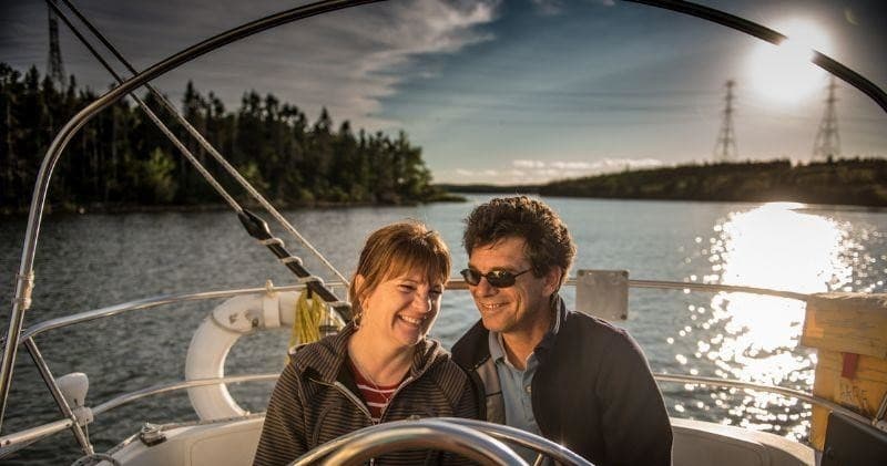 Couple at helm enjoying sunset sail with shimmering water