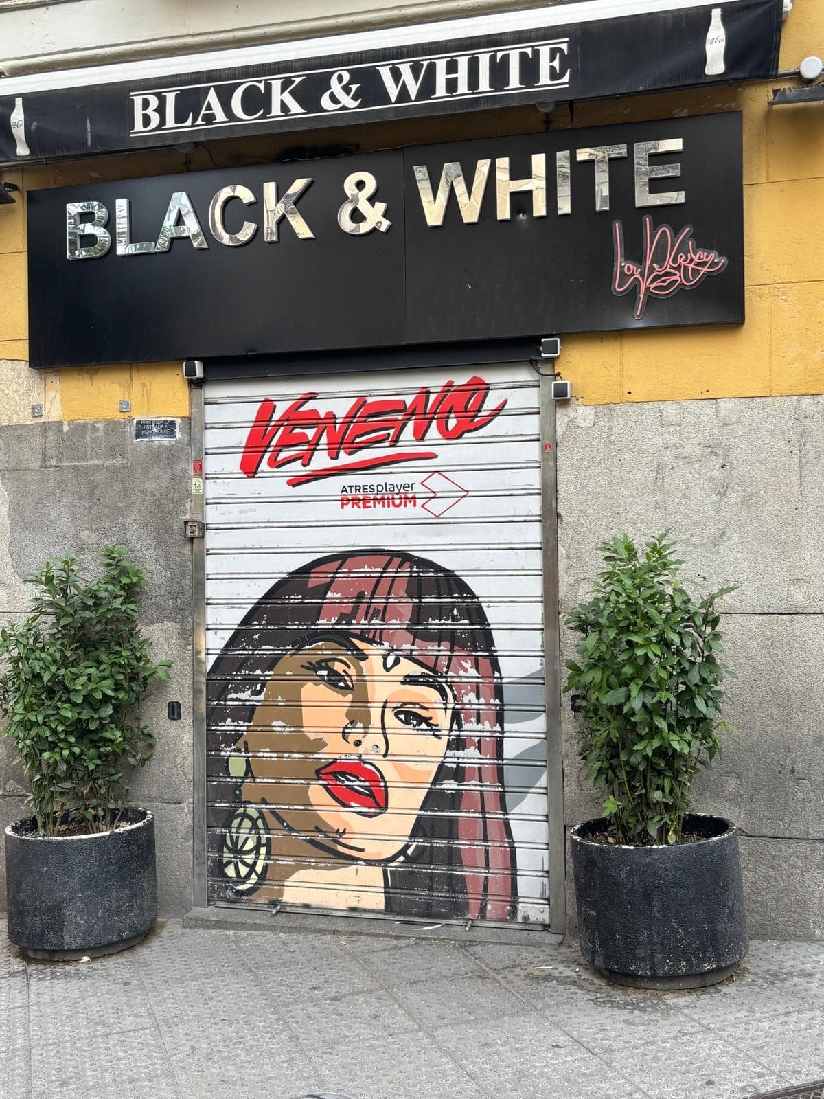 Street mural on shuttered Lisbon storefront with 'Black & White' sign