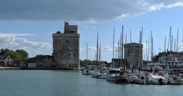 Sailboats moored in La Rochelle harbor with medieval towers