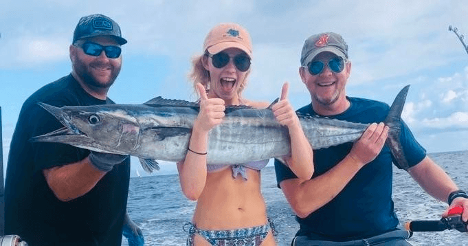 Three anglers proudly holding caught wahoo on offshore charter