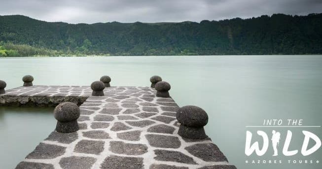 Stone jetty leading into tranquil crater lake, scenic walk