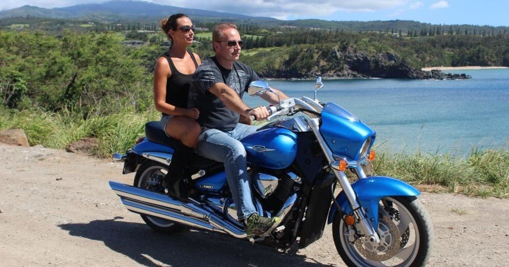 Couple riding cruiser motorcycle along scenic coastal road